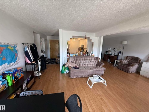 Spacious living area featuring wood-finish flooring, white walls, and a textured ceiling - 225 4404 122 Street, Edmonton, AB 