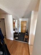 Entryway featuring wood-finish flooring transitioning to tile, a built-in shelving unit, a textured ceiling, and a flush-mount ceiling light - 