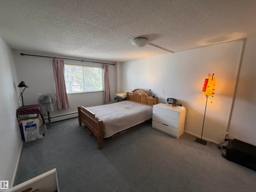 Carpeted bedroom with a single window featuring a white frame - 225 4404 122 Street, Edmonton, AB 