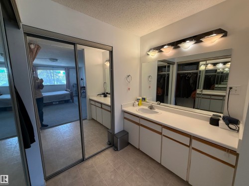 Bathroom vanity featuring a single basin sink, laminate countertop, and ample storage cabinetry - 225 4404 122 Street, Edmonton, AB 