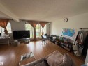 Spacious living area featuring wood-finish flooring, white walls, and a textured ceiling - 225 4404 122 Street, Edmonton, AB 