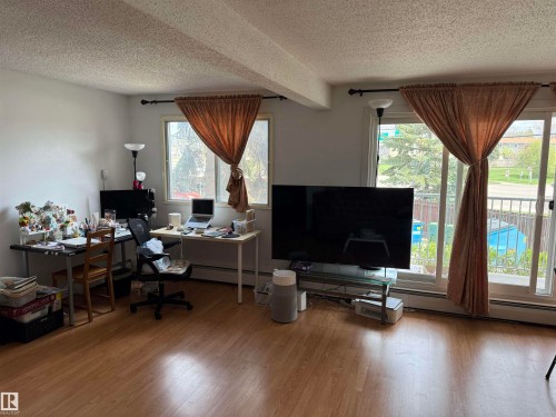 Living area featuring light wood-finish flooring, white walls, and a textured ceiling - 225 4404 122 Street, Edmonton, AB 