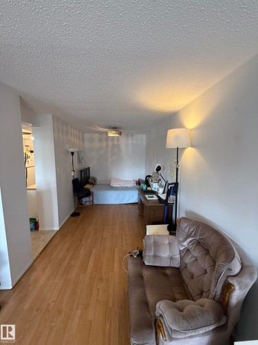 Open-concept living area featuring wood-finish flooring, white walls, and a textured ceiling - 225 4404 122 Street, Edmonton, AB 