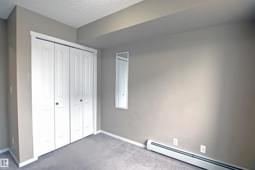 Bedroom featuring bi-fold closet doors, neutral wall paint, and gray carpet flooring - 215 1510 Watt Drive, Edmonton, AB 