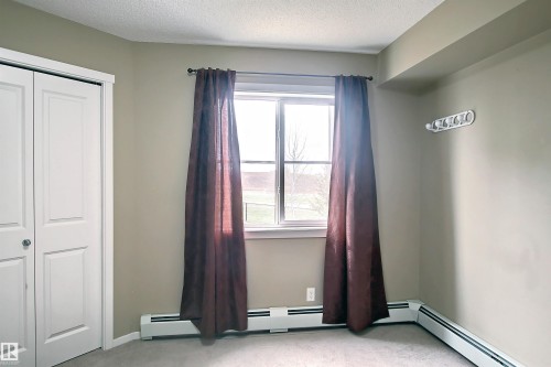 Bright window offering natural light, complemented by a white bi-fold closet - 215 1510 Watt Drive, Edmonton, AB 