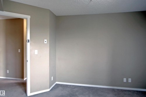 Room featuring neutral tone walls, white trim, and gray carpeting - 215 1510 Watt Drive, Edmonton, AB 