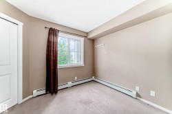 Carpeted interior space featuring a white door, large window with white trim, baseboard heating, and light tan wall color - 