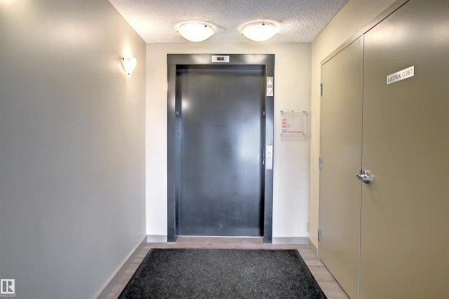 Residential elevator entrance with two surface-mounted ceiling lights and two wall sconces - 215 1510 Watt Drive, Edmonton, AB 