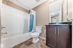 Bathroom featuring a dark wood-finish vanity with a dark stone countertop, undermount sink, and chrome faucet - 