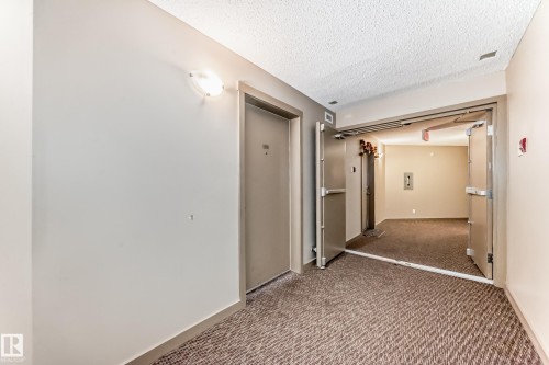 Corridor featuring textured carpeting, neutral wall finishes, and a textured ceiling - 215 1510 Watt Drive, Edmonton, AB 