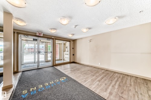 Spacious common area featuring light-toned walls, wood-finish flooring, and multiple ceiling-mounted light fixtures - 215 1510 Watt Drive, Edmonton, AB 