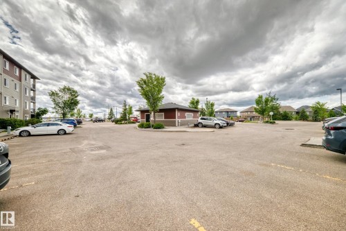 Expansive paved parking lot featuring marked spaces and mature trees - 215 1510 Watt Drive, Edmonton, AB 