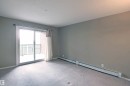 Carpeted room with neutral wall tones and a sliding glass door providing balcony access - 215 1510 Watt Drive, Edmonton, AB 