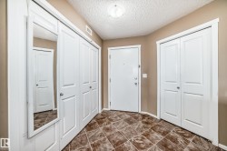 Entryway featuring a white door, brown tiled flooring, and multiple white bi-fold closet doors - 