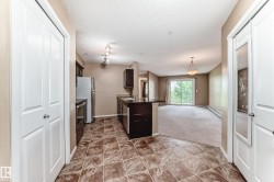 Kitchen featuring rich wood-finish cabinetry, stainless steel appliances, dark countertops, and patterned tile flooring - 