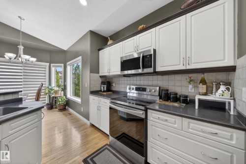Contemporary kitchen featuring white cabinetry, stainless steel appliances, and dark countertops - 4113 59 Street, Beaumont, AB 