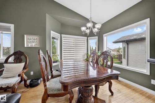 Dining area with wood-finish flooring, olive-toned walls, and a multi-pane window configuration - 4113 59 Street, Beaumont, AB 