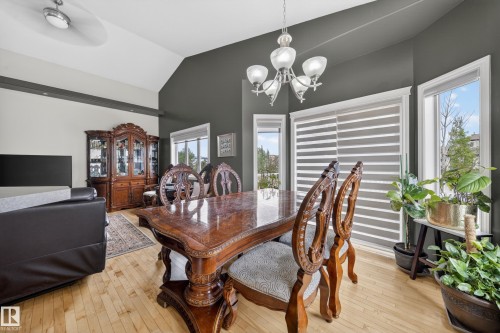 Dining area featuring a decorative chandelier, light wood-finish flooring, and multiple windows with horizontal blinds - 4113 59 Street, Beaumont, AB 