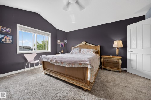 Vaulted ceiling bedroom featuring a large window, neutral carpet flooring, and a ceiling fan - 4113 59 Street, Beaumont, AB 
