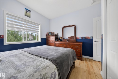 Bedroom featuring light wood-finish flooring, a white window frame, and white trim - 4113 59 Street, Beaumont, AB 