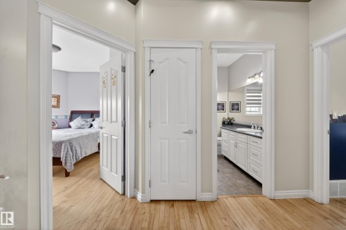 Hallway featuring light wood-finish flooring, white paneled doors, and clean trim work - 4113 59 Street, Beaumont, AB 