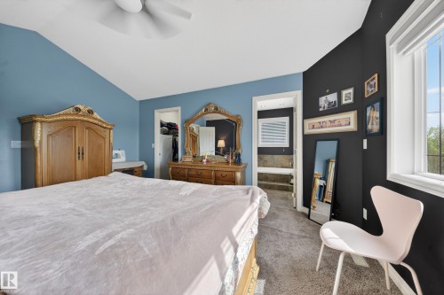 Carpeted interior room featuring a vaulted ceiling with a ceiling fan, a window with horizontal blinds, and a doorway leading to an interior staircase - 4113 59 Street, Beaumont, AB 