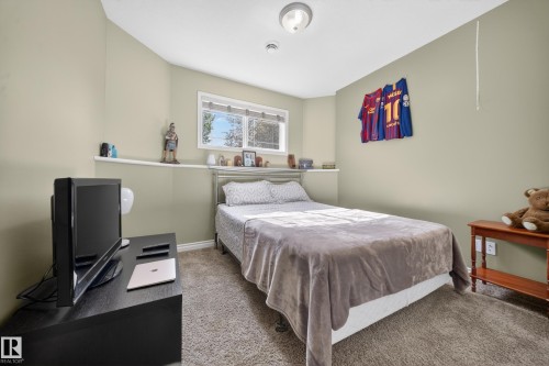Carpeted room featuring a window with white blinds, a built-in shelf below the window, and a flush-mount ceiling light fixture - 4113 59 Street, Beaumont, AB 