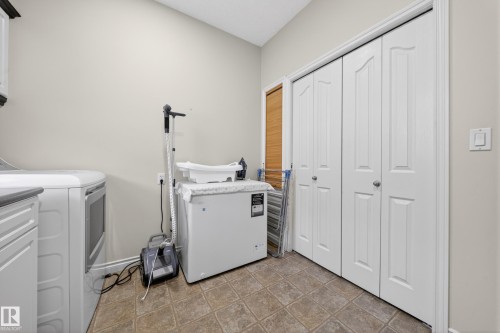 Utility area featuring bi-fold doors, tiled flooring, and a light wall color - 4113 59 Street, Beaumont, AB 