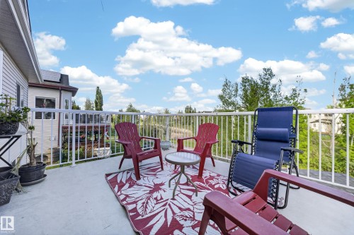 Spacious outdoor deck featuring a white railing, a concrete surface, and surrounding greenery - 4113 59 Street, Beaumont, AB 