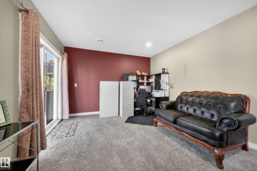 Spacious interior room featuring light-colored carpet flooring and a neutral wall color complemented by a distinct accent wall - 4113 59 Street, Beaumont, AB 