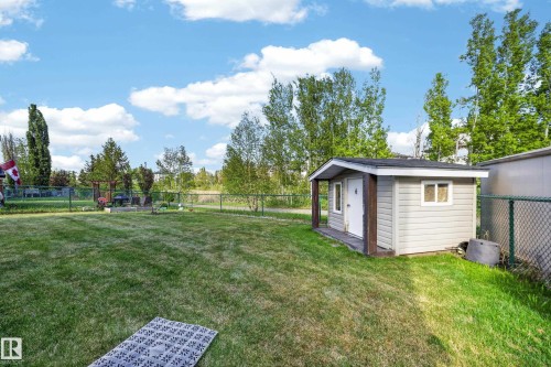 Expansive backyard featuring a storage shed with siding, a chain-link fence, and mature trees - 4113 59 Street, Beaumont, AB 