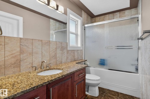 Expansive kitchen featuring wood cabinetry, granite countertops, and a black tile backsplash - 1508 Palmer Close, Edmonton, AB 