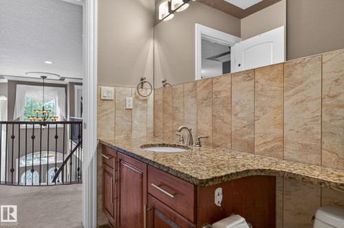 Open-concept living space featuring a custom built-in entertainment center with integrated fireplace, tray ceilings with recessed lighting and decorative crown molding, and tiled flooring - 1508 Palmer Close, Edmonton, AB 