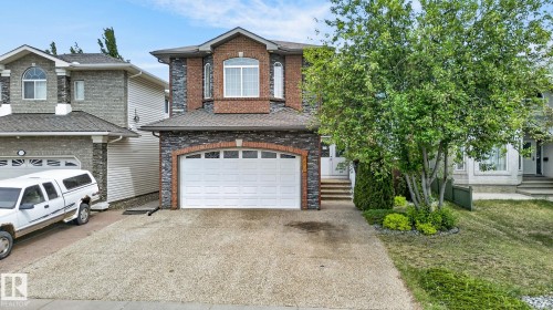 Carpeted bedroom featuring a double-door bi-fold closet, two windows with exterior views, and a ceiling-mounted light fixture - 1508 Palmer Close, Edmonton, AB 