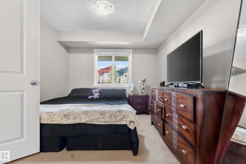 Carpeted room with a window providing natural light, featuring a ceiling-mounted light fixture - 225 1510 Watt Drive, Edmonton, AB - Indoor Photo Showing Bedroom