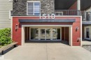Entryway featuring automatic glass doors, red siding, stone accents, exterior lighting fixtures, and a prominent building number - 225 1510 Watt Drive, Edmonton, AB  - Outdoor With Exterior 