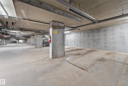 Concrete subterranean parking area featuring exposed ceiling utilities and structural columns - 225 1510 Watt Drive, Edmonton, AB - Indoor Photo Showing Garage