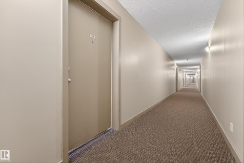 Long interior corridor with textured carpet flooring and light neutral wall paint - 225 1510 Watt Drive, Edmonton, AB - Indoor Photo Showing Other Room