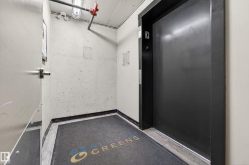 Elevator access within a common area, featuring industrial-style exposed piping and a durable floor mat - 225 1510 Watt Drive, Edmonton, AB - Indoor Photo Showing Other Room