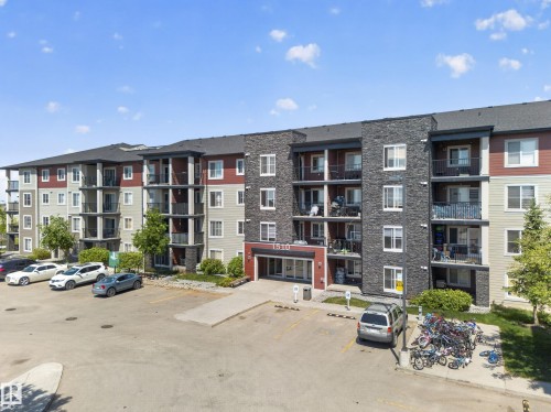Multi-story building featuring a stone and siding facade, private balconies, a designated parking area, and a prominent main entrance - 225 1510 Watt Drive, Edmonton, AB - Outdoor With Facade