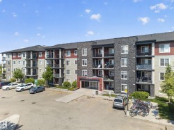 Multi-story building featuring a stone and siding facade, private balconies, a designated parking area, and a prominent main entrance - 