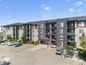 Multi-story building featuring a stone and siding facade, private balconies, a designated parking area, and a prominent main entrance - 225 1510 Watt Drive, Edmonton, AB  - Outdoor With Facade 