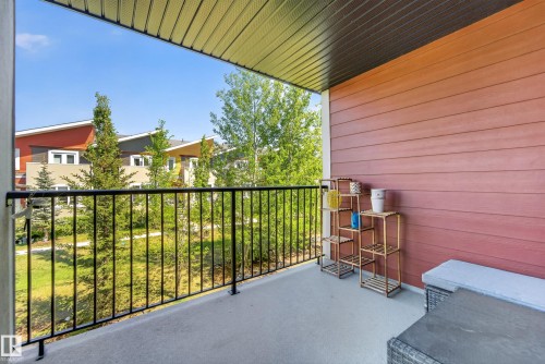 Private balcony with concrete flooring, black metal railing, and horizontal wood-finish siding - 225 1510 Watt Drive, Edmonton, AB - Outdoor With Deck Patio Veranda With Exterior