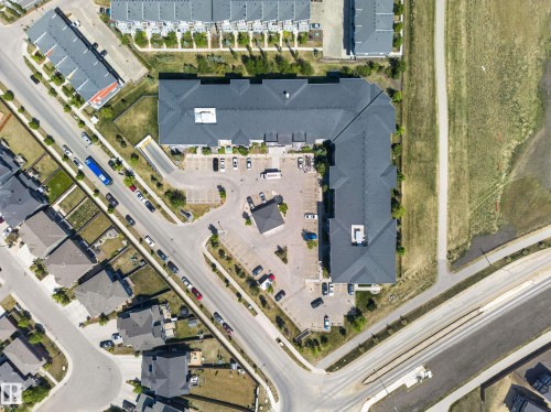Large commercial building featuring an asphalt shingle roof, expansive parking area, and surrounding paved roads - 225 1510 Watt Drive, Edmonton, AB - Other