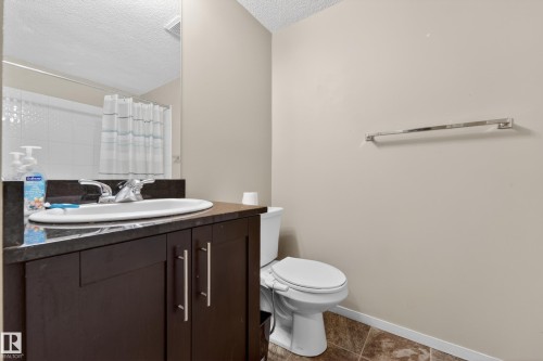Bathroom featuring a dark wood-finish vanity with a built-in sink, dark countertop, and chrome faucet - 225 1510 Watt Drive, Edmonton, AB - Indoor Photo Showing Bathroom