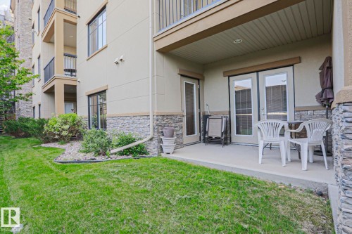 Ground-level patio featuring double French doors and stone veneer siding - 117 160 Magrath Road, Edmonton, AB - Outdoor With Deck Patio Veranda