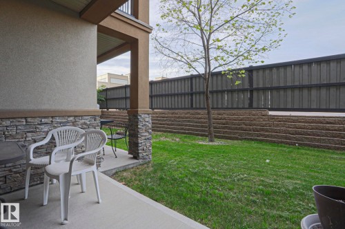 Covered patio area with concrete flooring, stone veneer accents, and stucco siding - 117 160 Magrath Road, Edmonton, AB - Outdoor With Deck Patio Veranda
