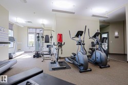 Dedicated fitness room featuring multiple exercise machines, expansive windows, carpet flooring, and recessed lighting - 