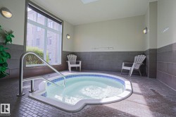 Indoor hot tub with a stainless steel grab rail, mosaic tile detailing, and a large window - 