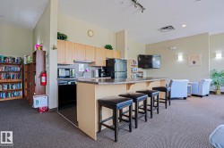 Functional kitchen area featuring light wood-finish cabinetry, a black appliance suite, and a granite-style countertop - 